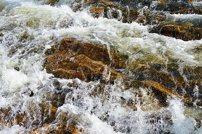 Detailaufnahme einer Stromschnelle auf rotem Gestein im Børgefjell Nationalpark
